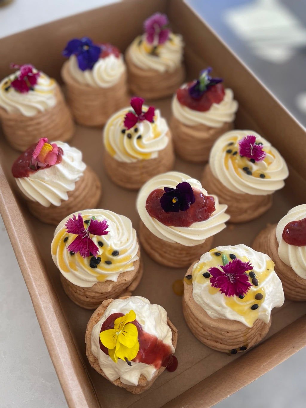 Mini pavlovas topped with cream, fruit and edible flowers