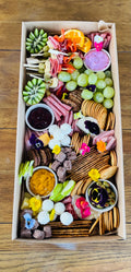 Charcuterie grazing box with cured meats, cheeses, dips, crackers, fruit and accompaniments