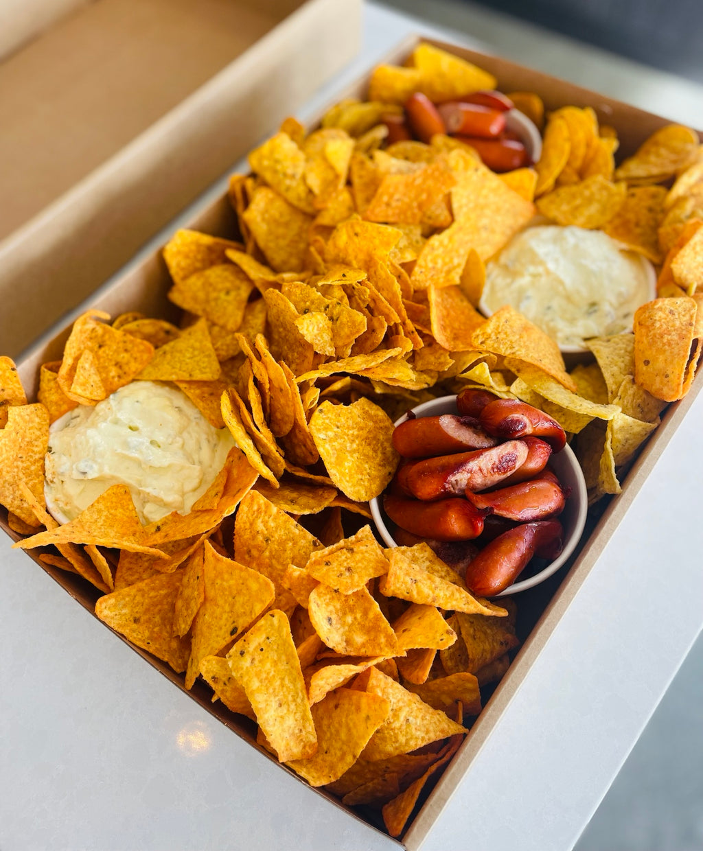Platter box with corn chips, creamy dips and sausages